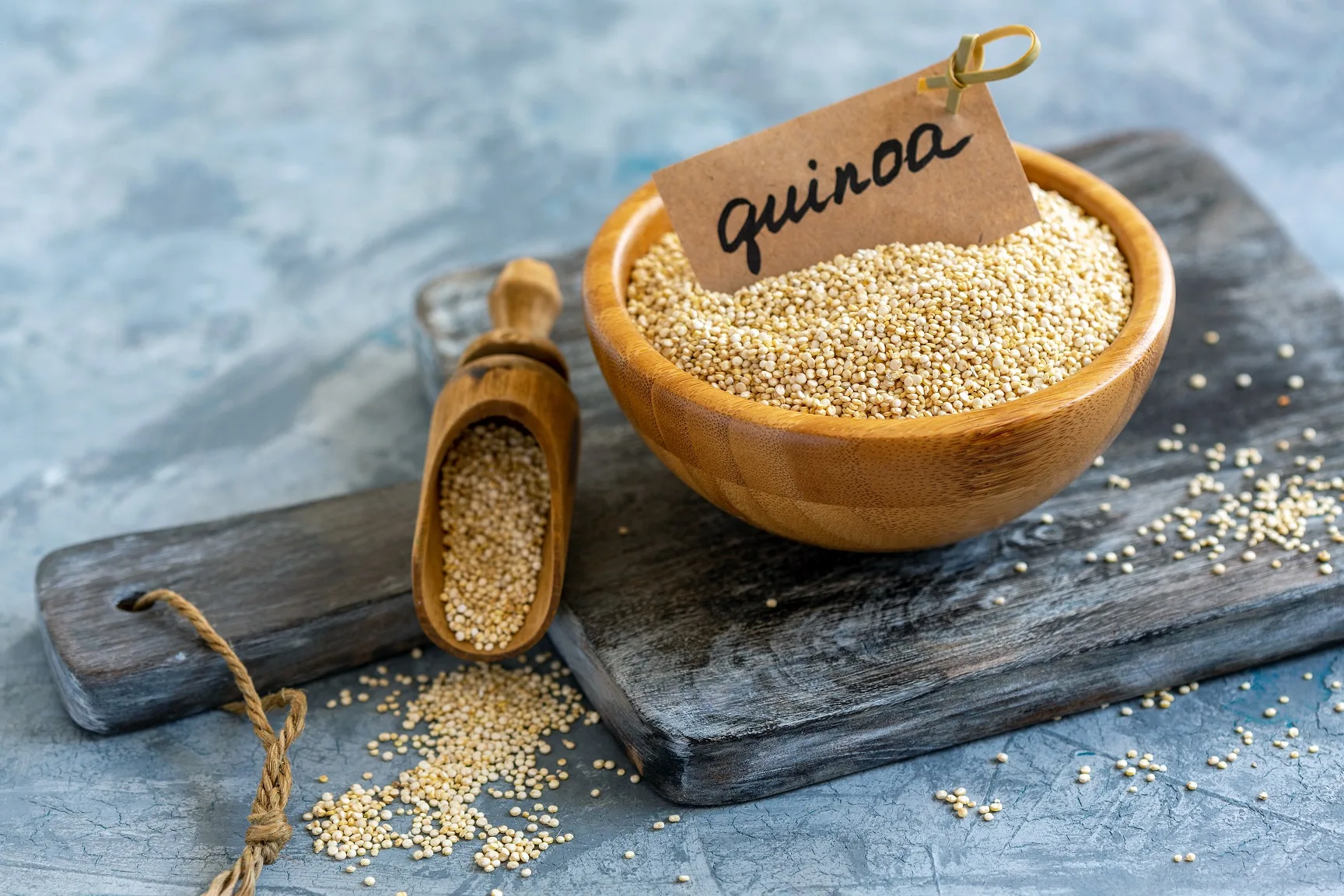 Bowl with white quinoa on an old wooden serving board, selective focus.