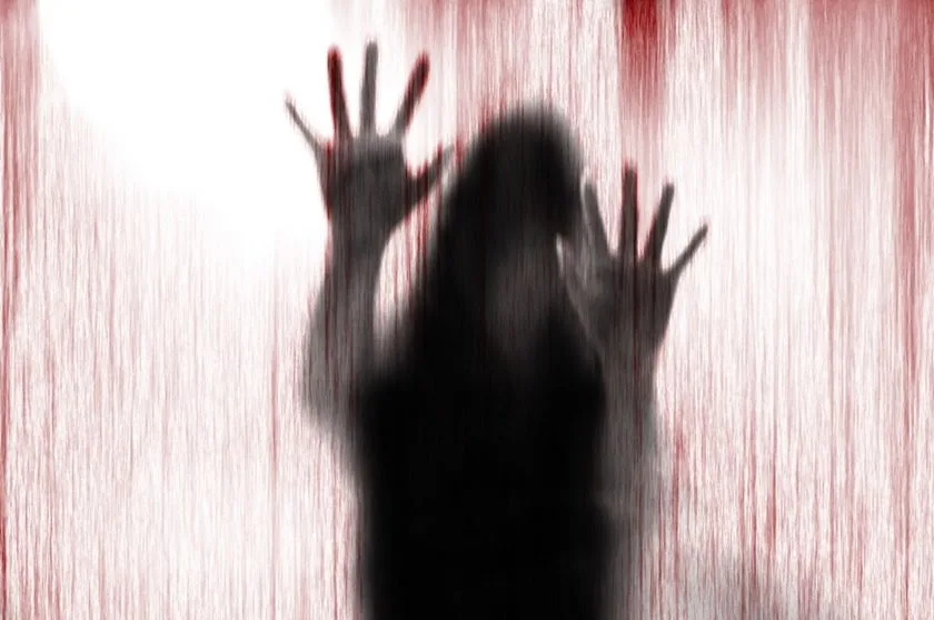 Horror woman behind the matte glass blood stain. Blurry hand and body figure abstraction.