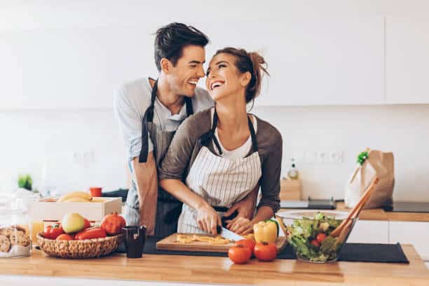 Affectionate couple preparing salad in a domestic kitchen