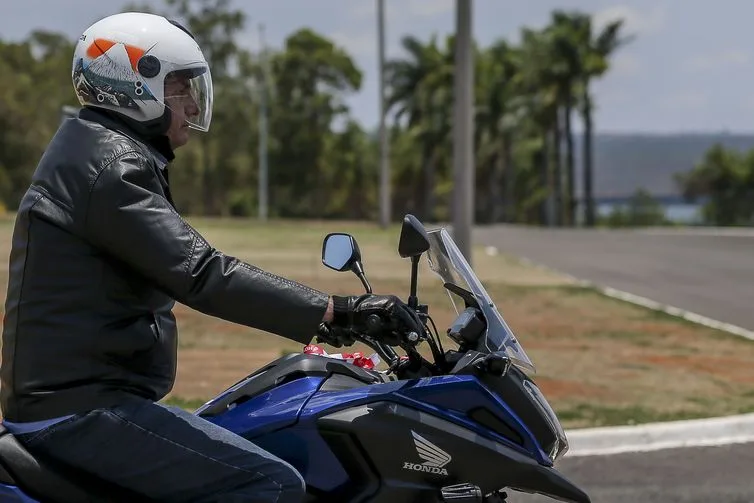 O presidente Jair Bolsonaro chega de moto no Palácio da Alvorada e cumprimenta turistas