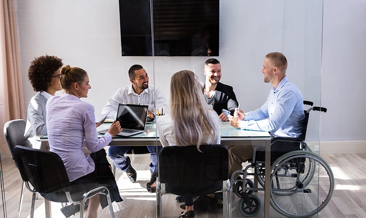 Disabled Male Manager Sitting With His Colleagues At Workplace