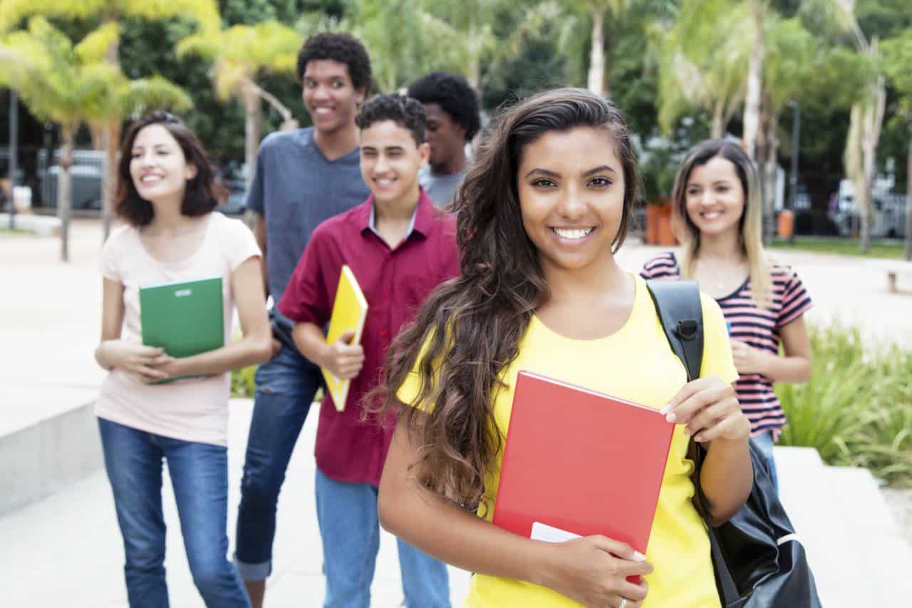 Latin american female student with group of international students outdoor in the summer in the city