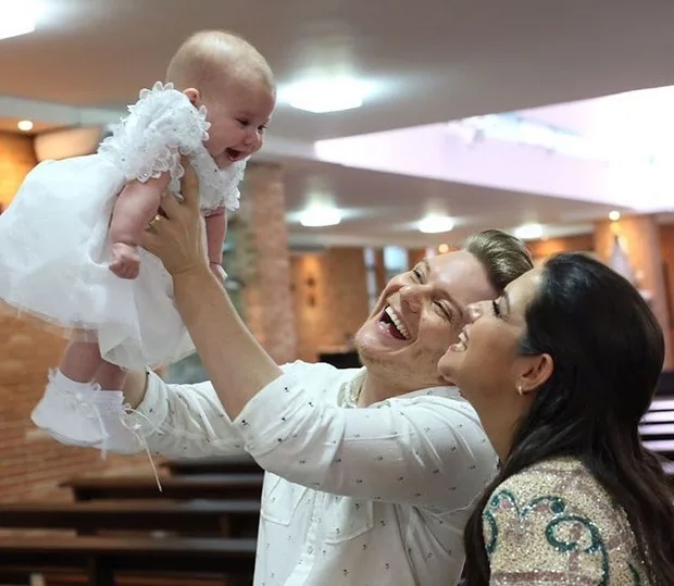 Michel Teló e Thaís Fersoza posam com Melinda durante batizado