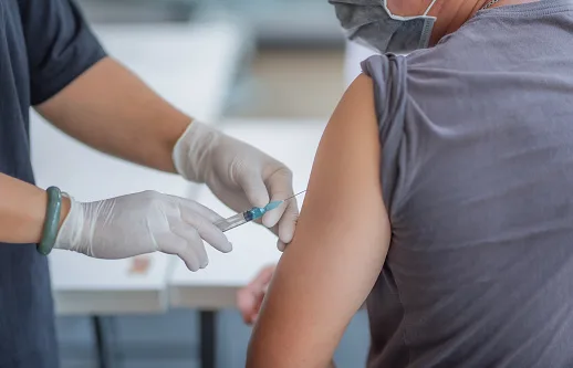 The doctor is injecting male patients.In the medical’s hand have syringes.