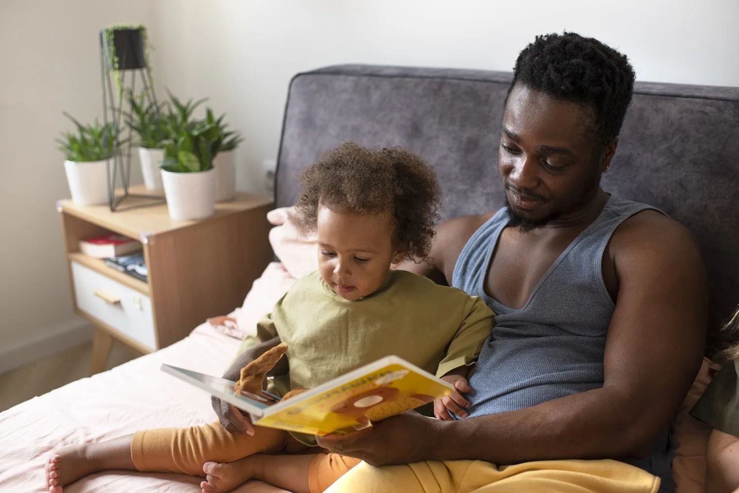 Pai lendo livro para seu filho, na cama | Foto: Freepik