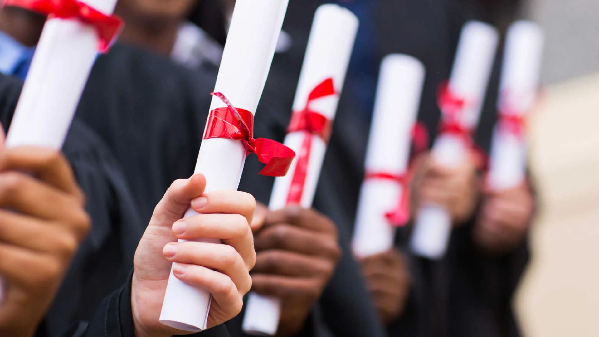 group of multiracial graduates holding diploma