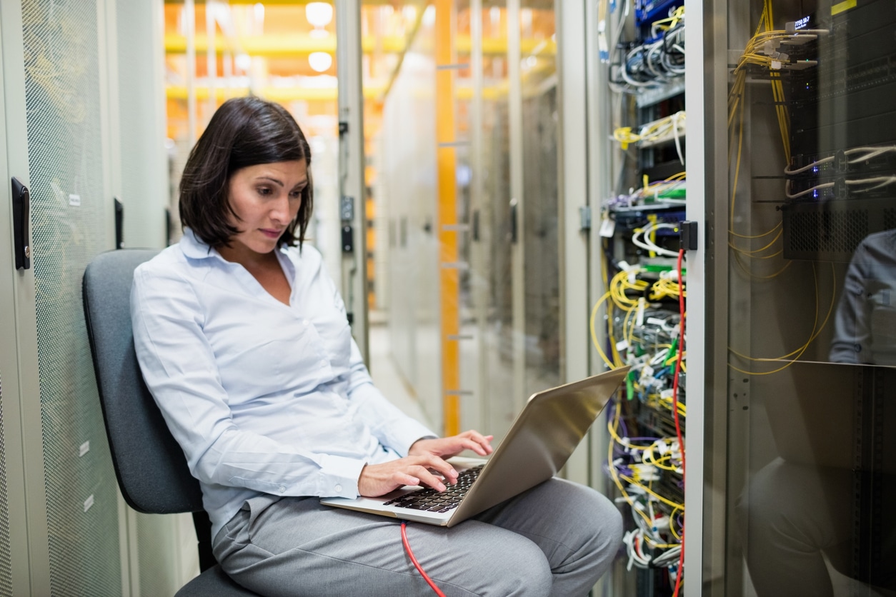 Attentive technician working on laptop in server room