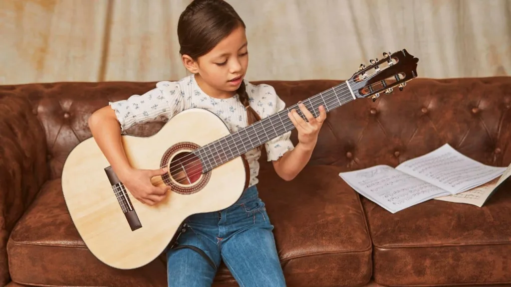 Criança aprende a tocar violão