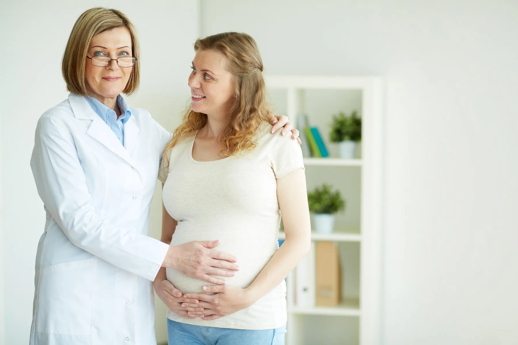 Happy pregnant woman and her doctor after regular examination at hospital