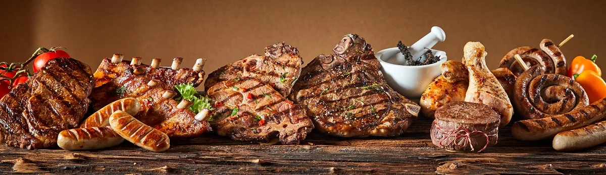 A selection of grilled gourmet meats on a rustic timber board.