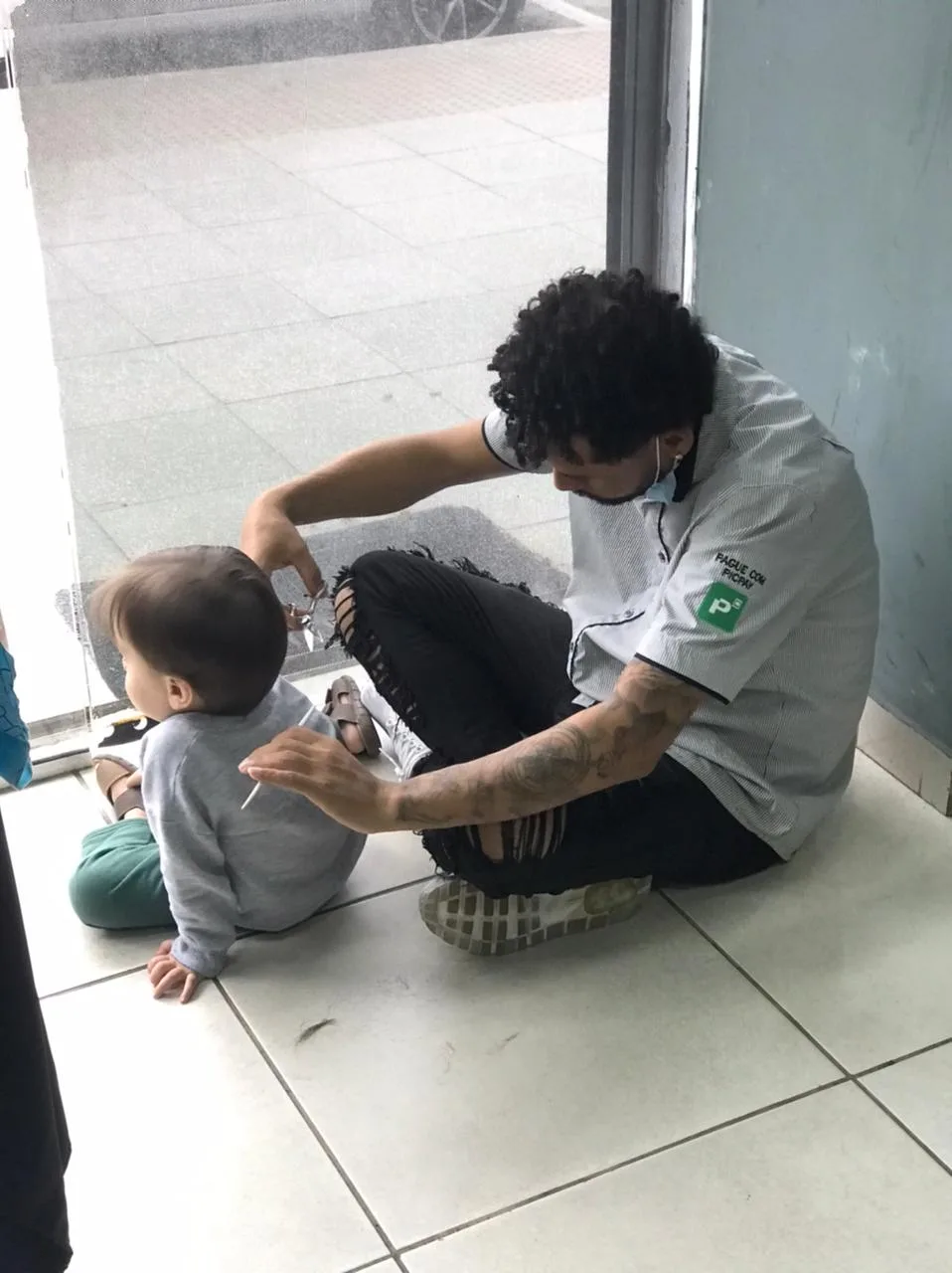 Dono de barbearia senta no chão para cortar o cabelo de criança autista