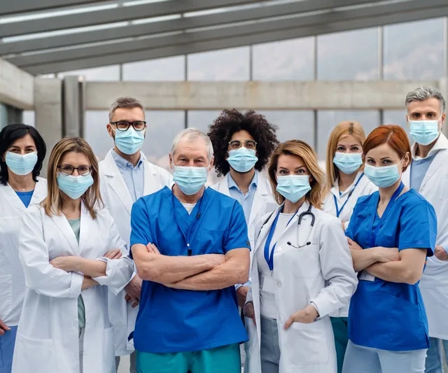 A group of doctors with face masks looking at camera, corona virus concept.