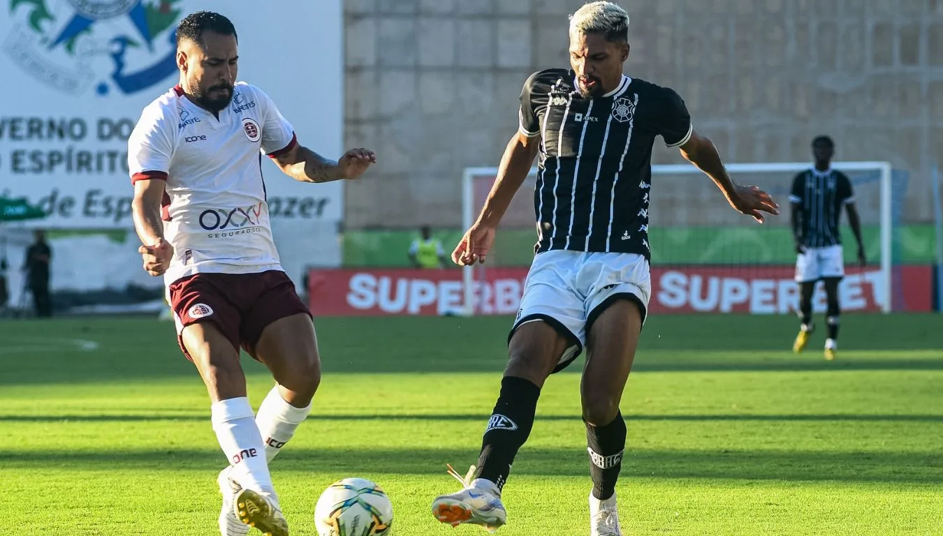 Jogador da Desportiva disputa a bola, com o pé, com jogador do Rio Branco