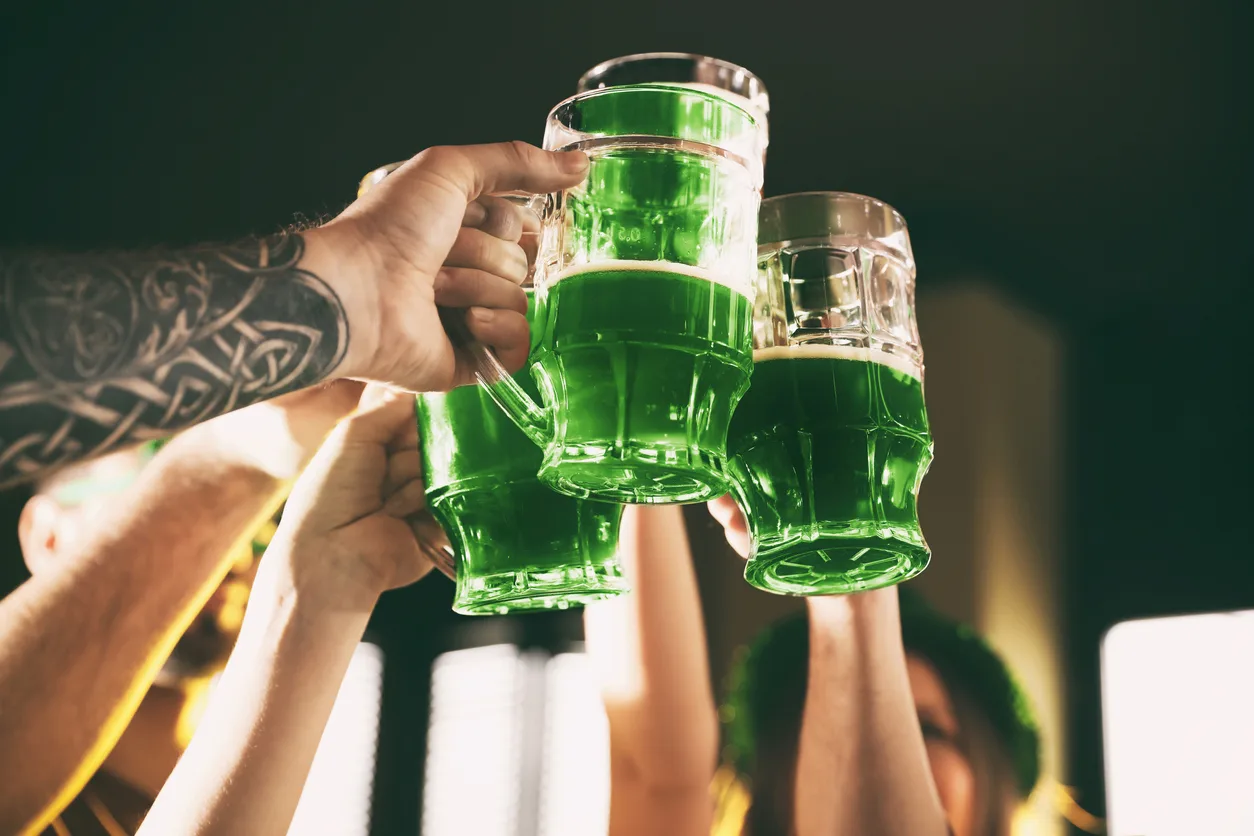 Group of friends toasting with green beer in pub, closeup. St. Patrick’s Day celebration