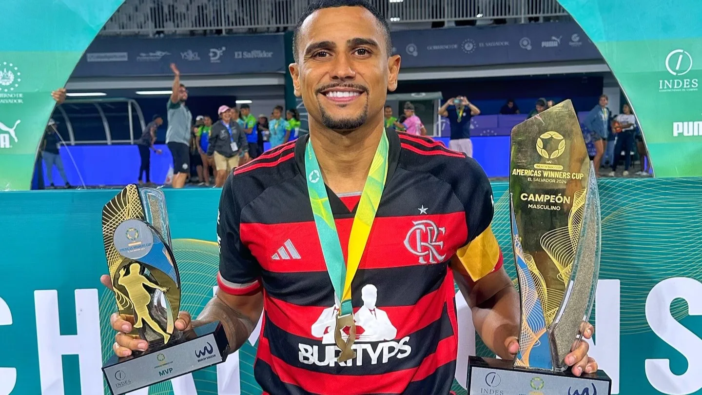 Rodrigo com a camisa do Flamengo e segurando um troféu em cada mão da America Winners Cup de Beach Soccer