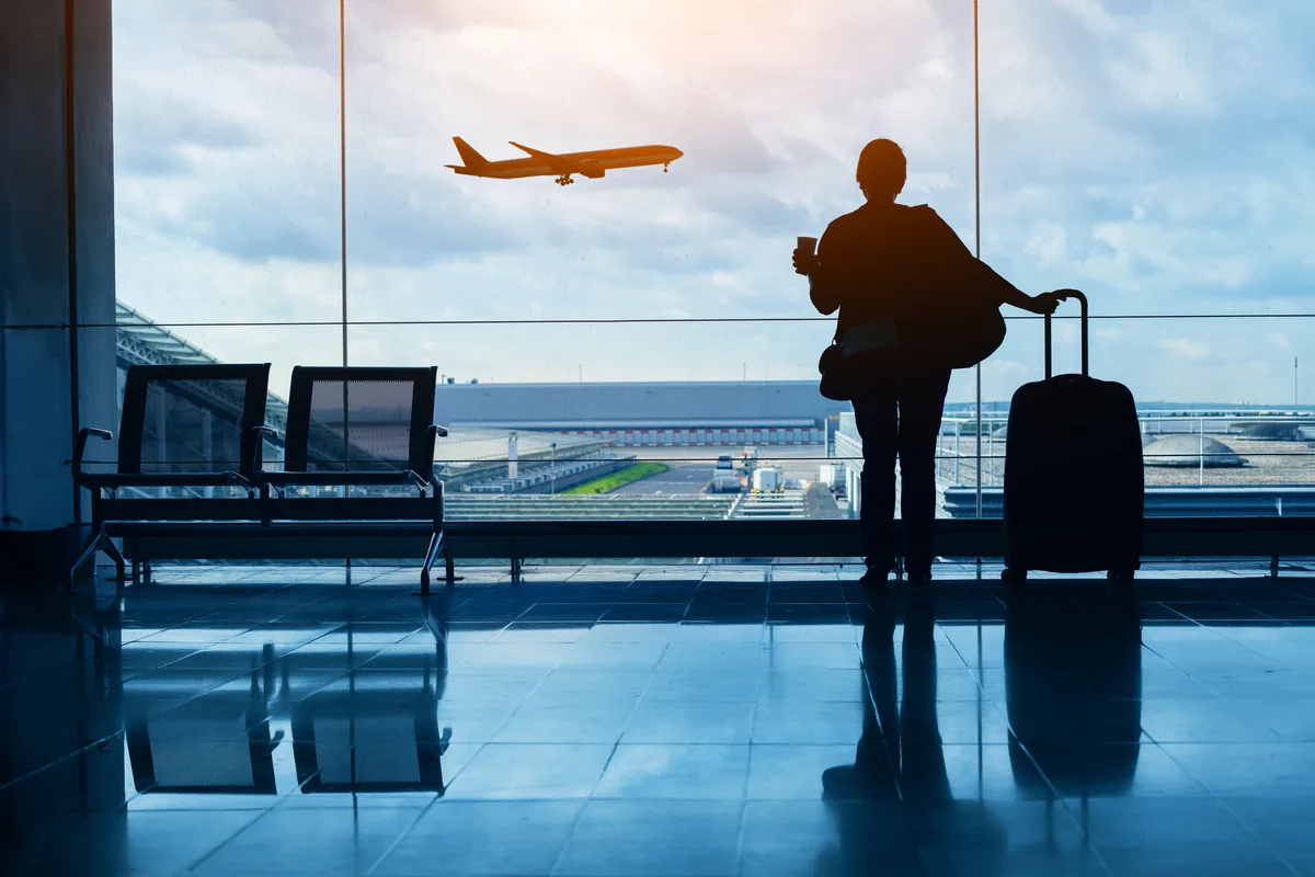 travel by plane, woman passenger waiting in airport, silhouette of passenger in airport watching aircraft taking off