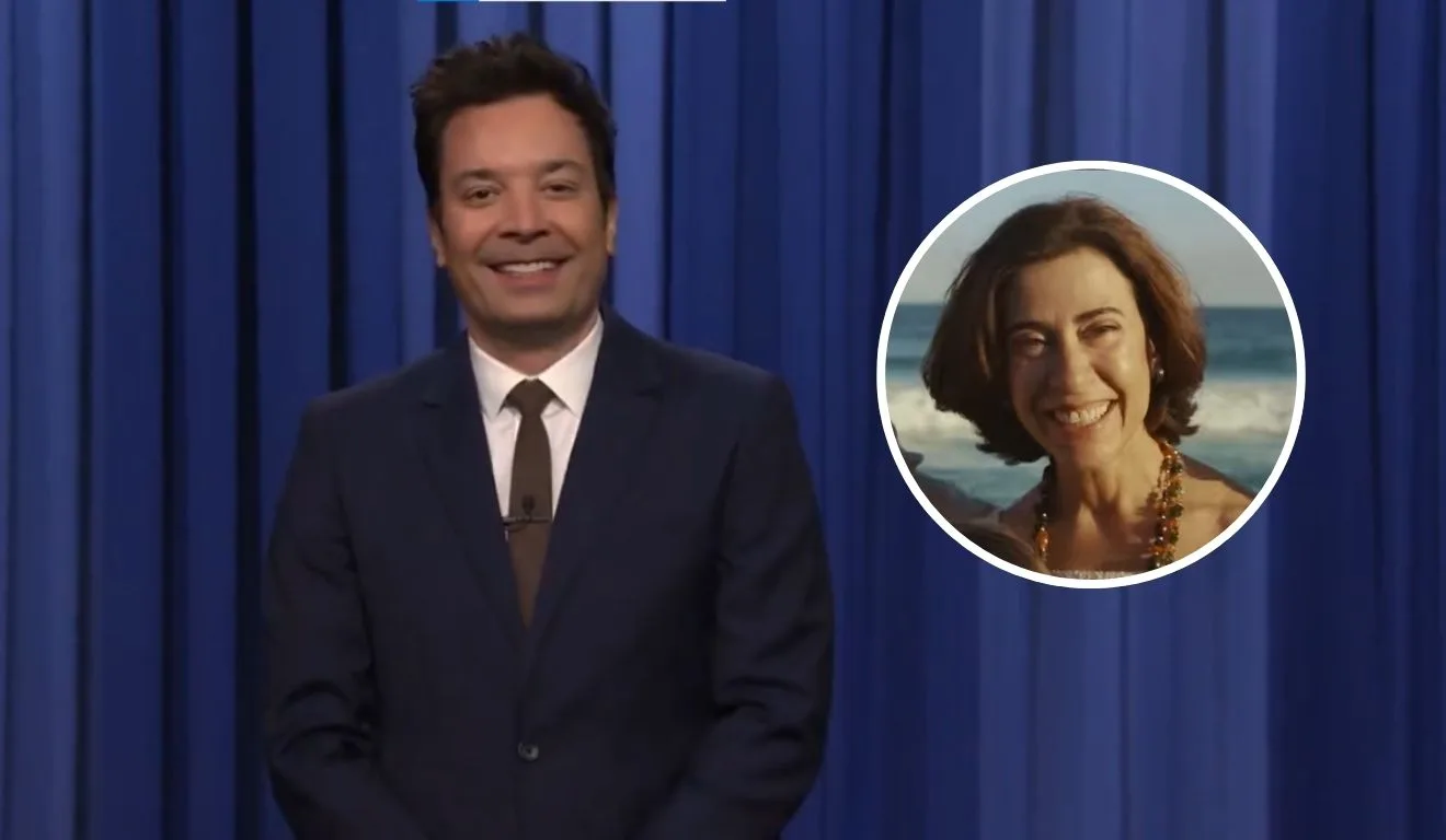 Jimmy Fallon, um homem branco, de cabelo curto e castanho, usando um terno, com gravata vermelha. Em destaque, em um circulo, Fernanda Torres em uma cena do filme Ainda Estou Aqui.