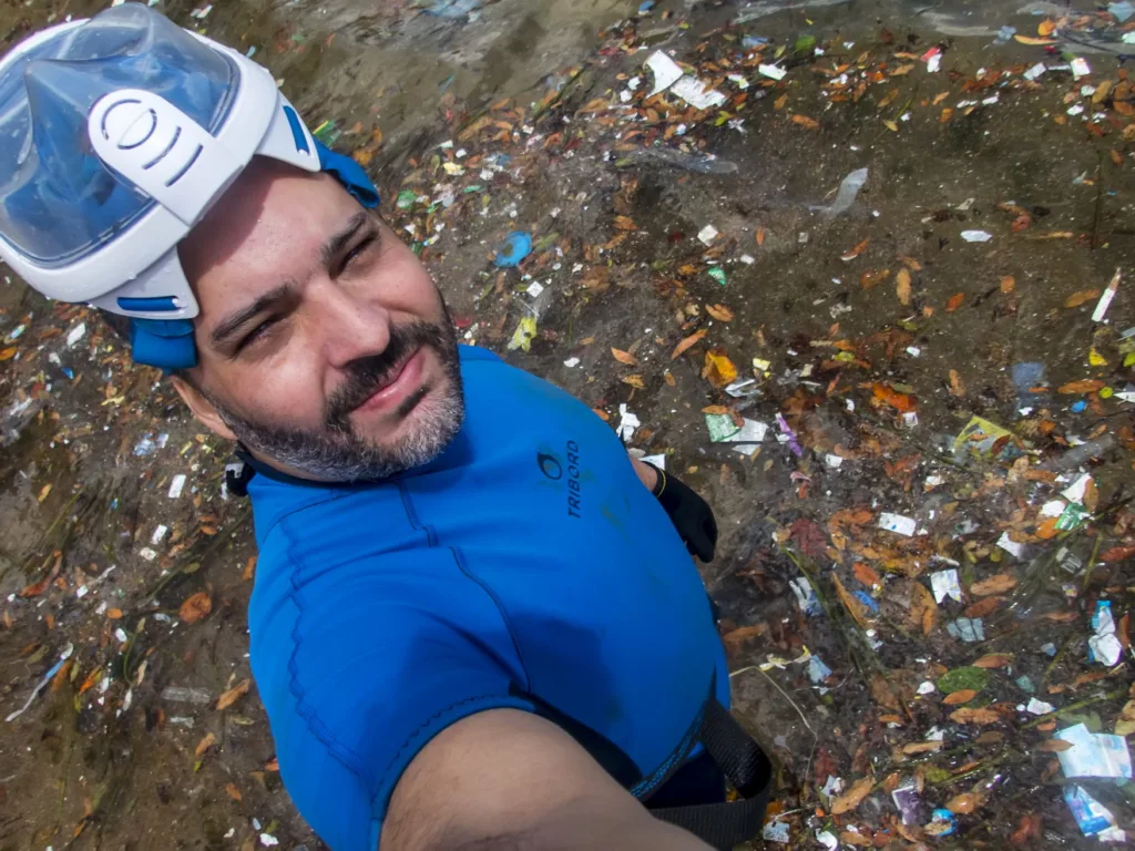 Fotógrafo Leonardo Merçon em meio a montes de resíduos na praia da Ilha do Boi, em Vitória, demonstrando a presença do lixo no ambiente natural