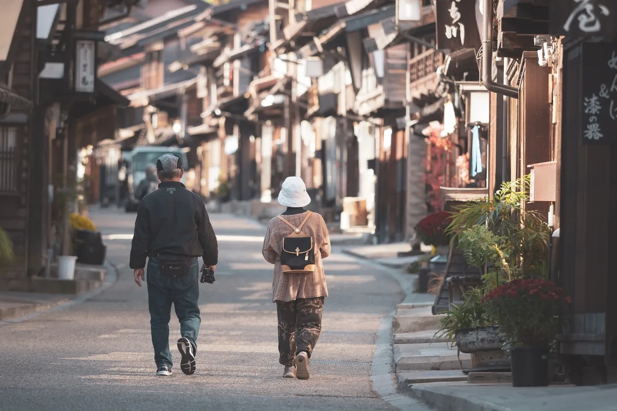 Rear view of senior couple walking on the road in Narai-juku, Japan-Old wooden house in Nagano, japan.