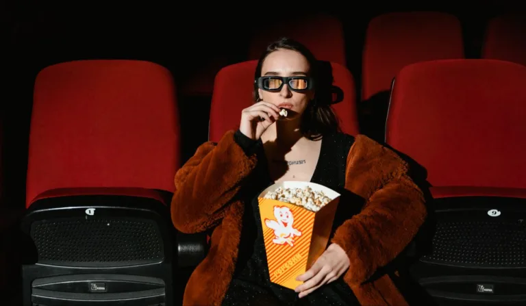 Mulher sentada em uma cadeira de cinema comendo pipoca