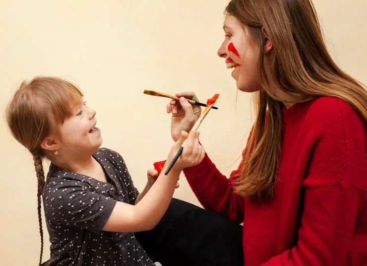 Criança e adulta brincando com pincel e tinta