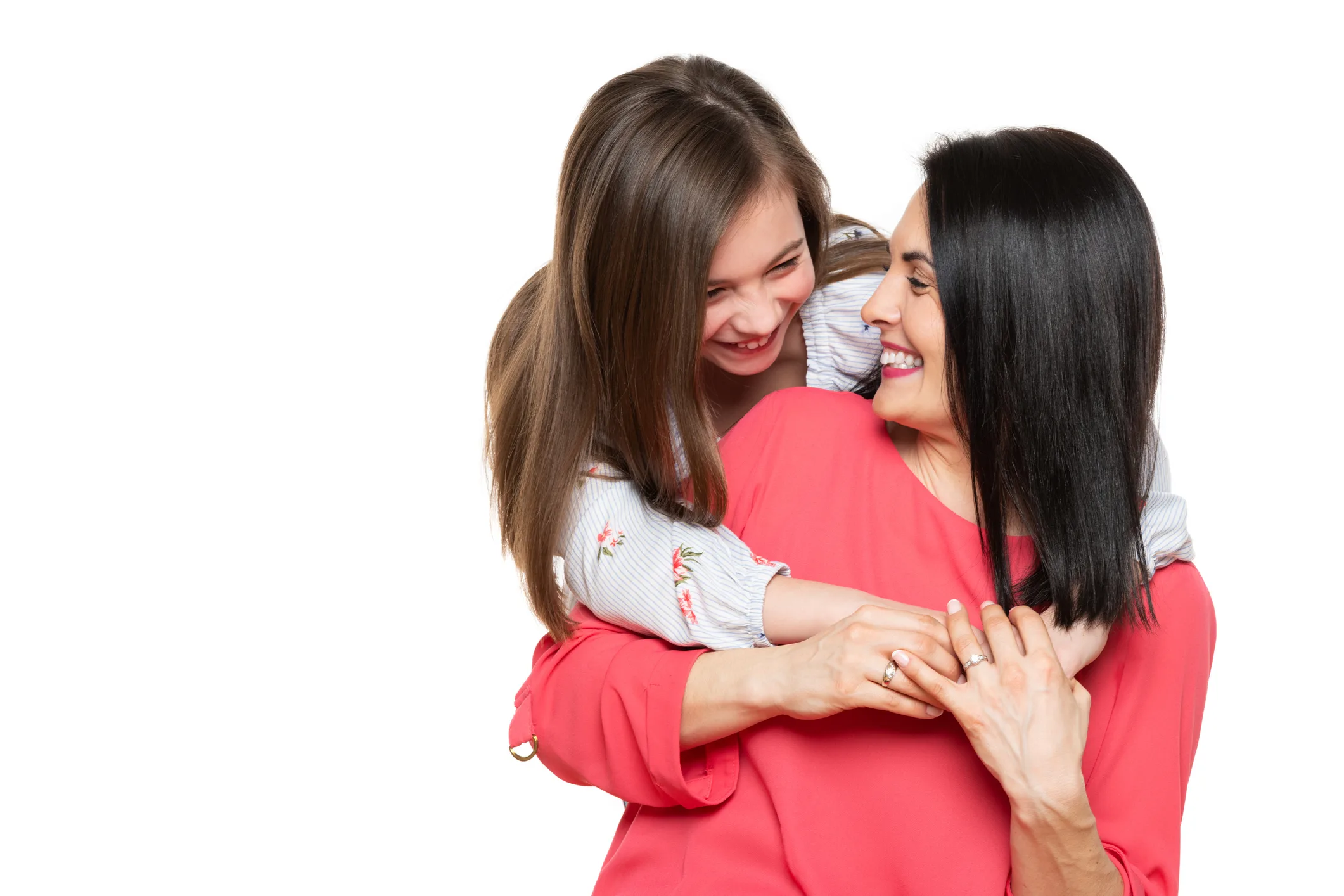 Waist up studio portrait of cute and playful schoolgirl embracing her mother. Happy family laughing background isolated over white.