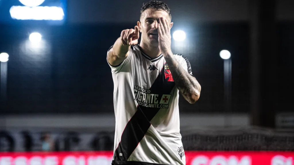 Vegetti, com o uniforme branco do vasco, tapa o olho esquerdo com a mão esquerda e comemora gol