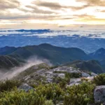 Vista panorâmica do horizonte a partir do Pico da Bandeira, com montanhas e nuvens compondo a paisagem