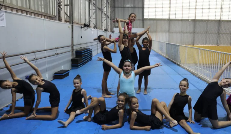 Treze meninas dançando balé em um ginásio