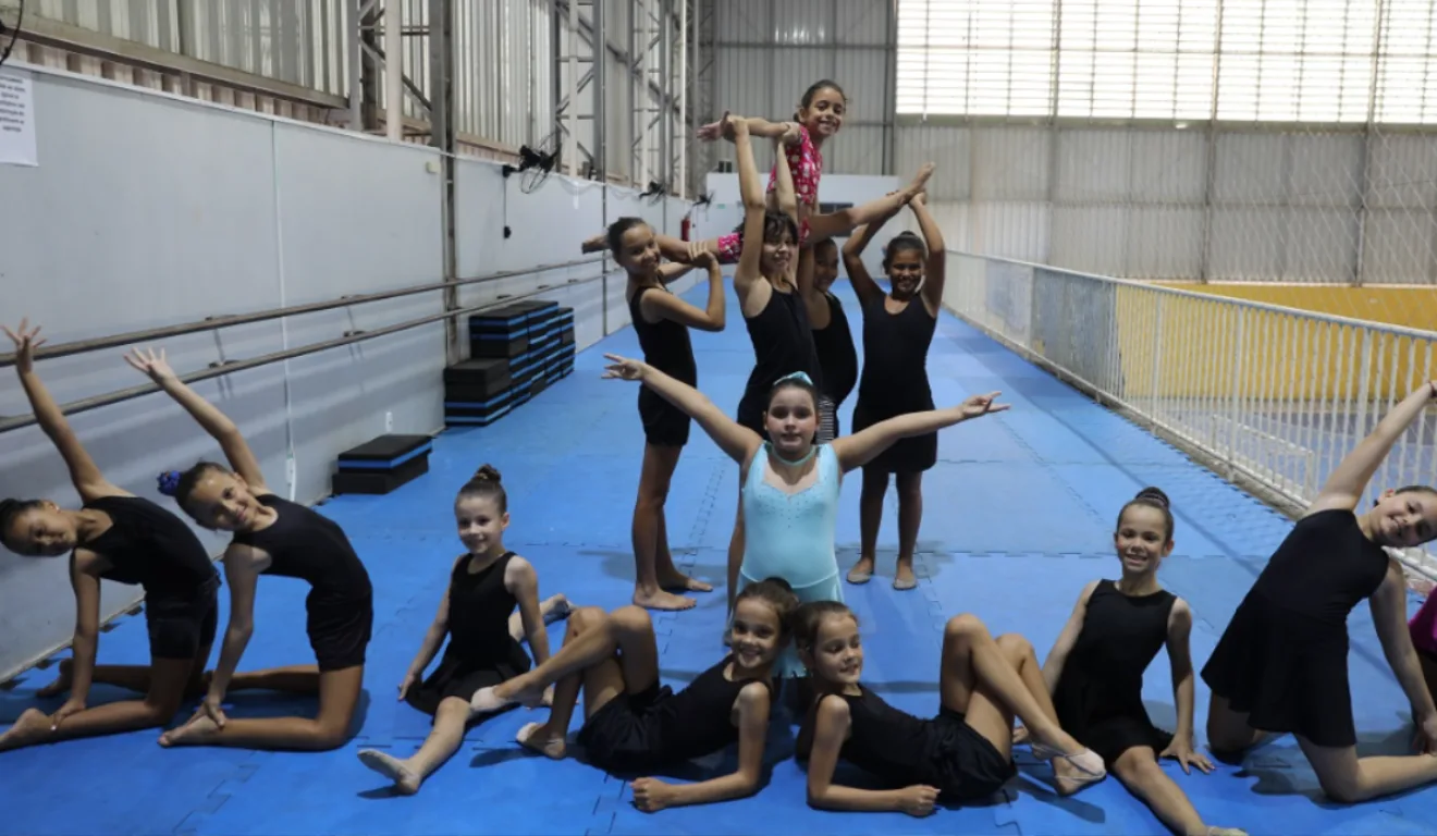 Treze meninas dançando balé em um ginásio