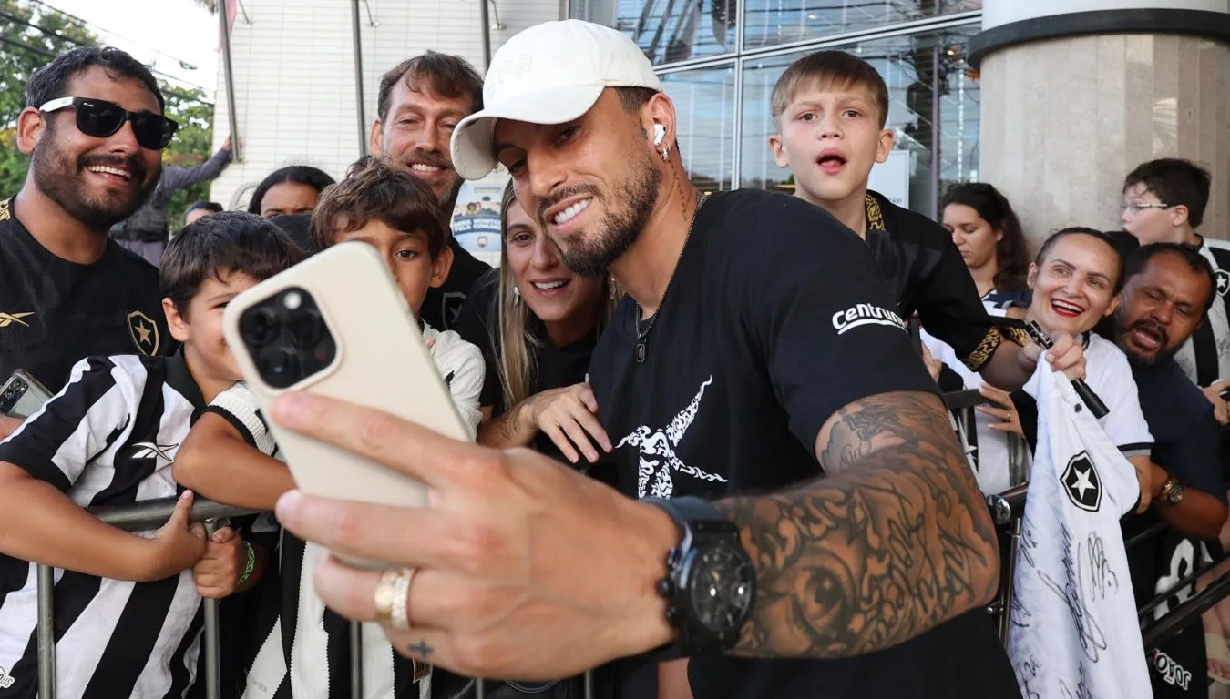 Alex Telles, do Botafogo, tira foto com torcedores na chegada do time ao Espírito Santo