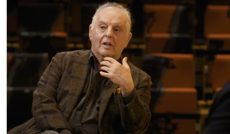 Daniel Barenboim está sentado e usa um terno marrom