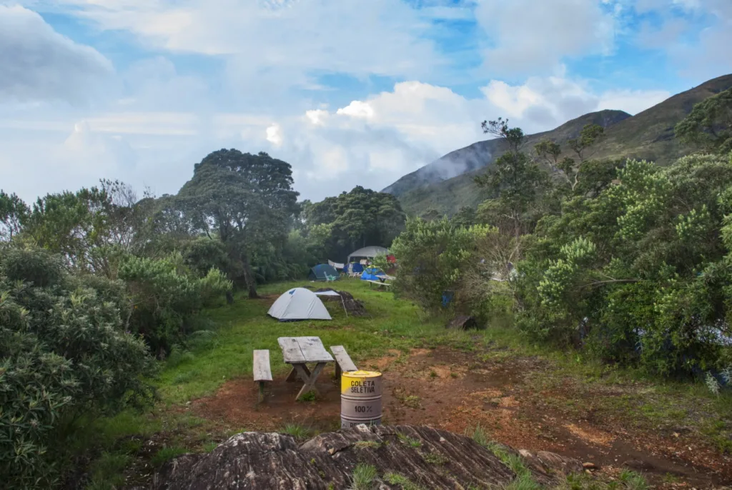 Área de camping no Parque Nacional do Caparaó, com barracas montadas em meio à paisagem montanhosa