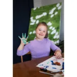 Garota com s&iacute;ndrome de Down com tinta nas m&atilde;os