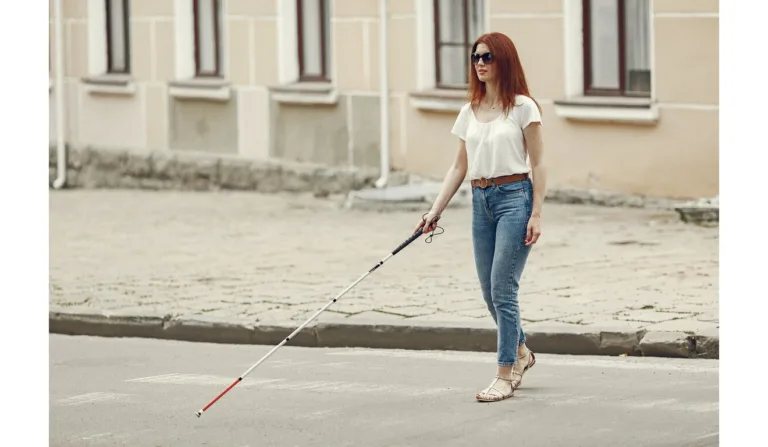 Mulher deficiente visual caminha pela cidade de bengala