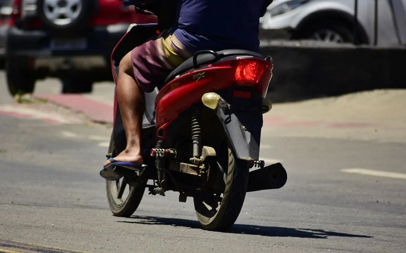Motociclista pilotando moto calçado com chinelo