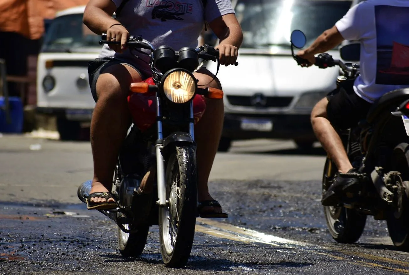 Motociclista pilotando moto calçado com chinelo