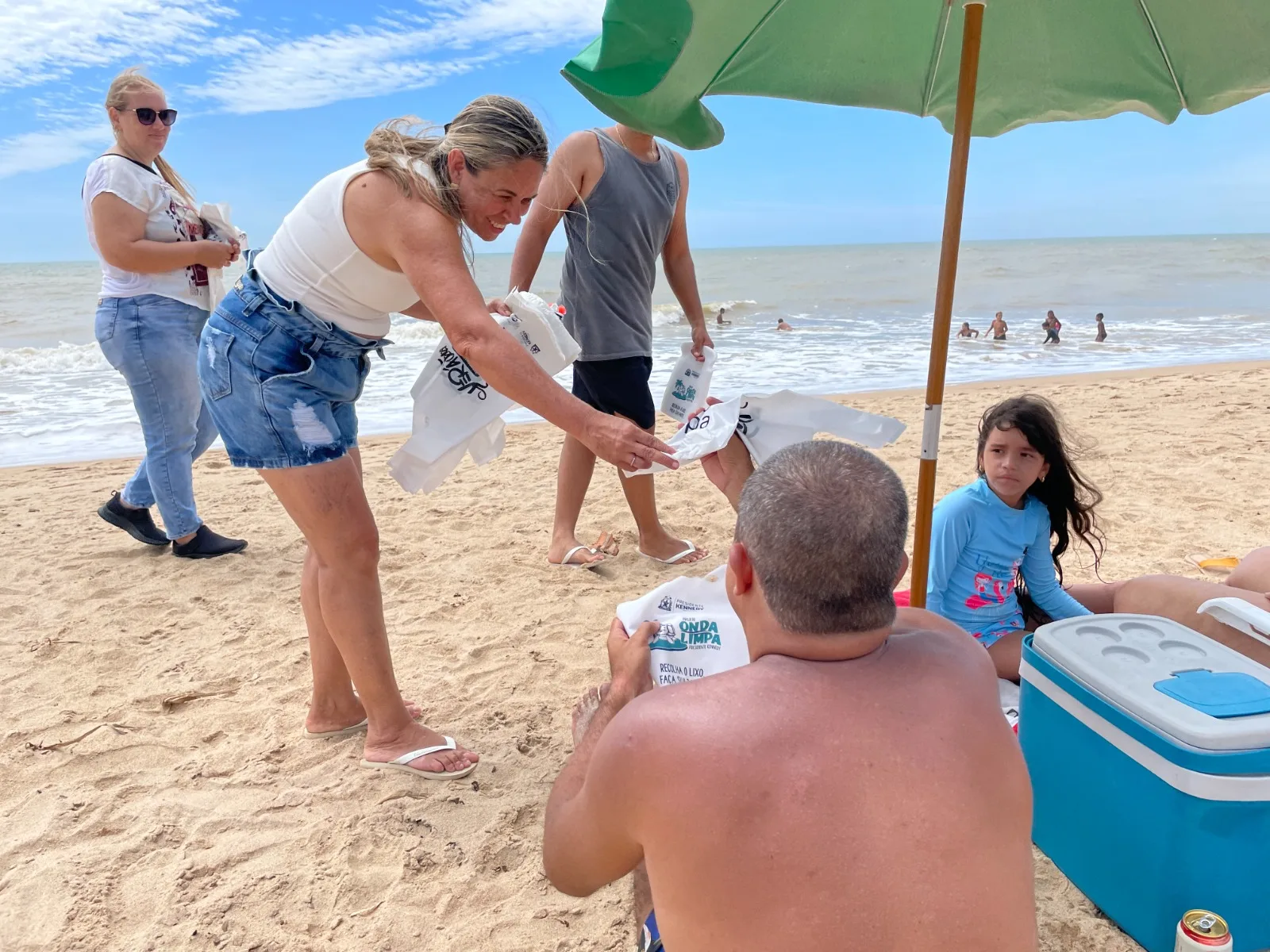 Banhistas auxiliam prefeitura na distribuição de kits biodegradáveis.
