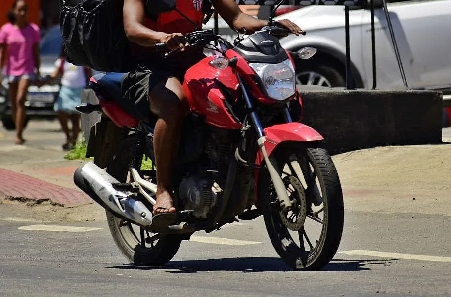 Motociclista pilotando moto calçado com chinelo