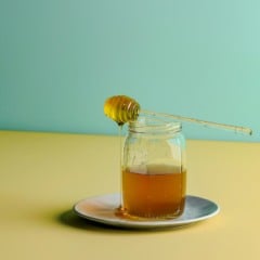 Copo com ch&aacute; de mel em mesa.